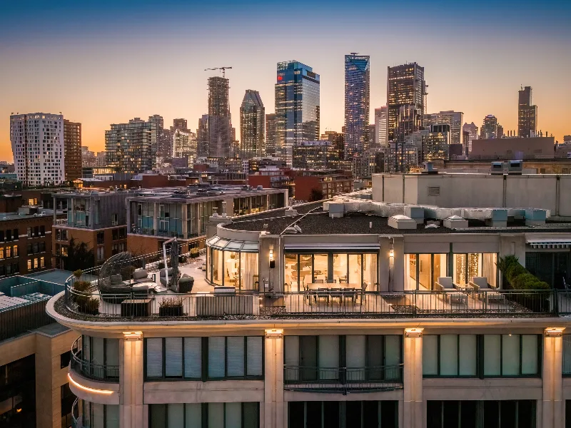 Le penthouse du 1 McGill et sa terrasse ceinturante au crépuscule, devant les tours du centre-ville de Montréal